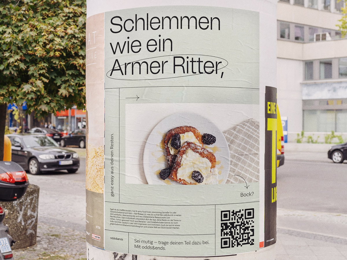 Poster reading "Schlemmen wie ein Armer Ritter" on a street corner next to a snack stand.