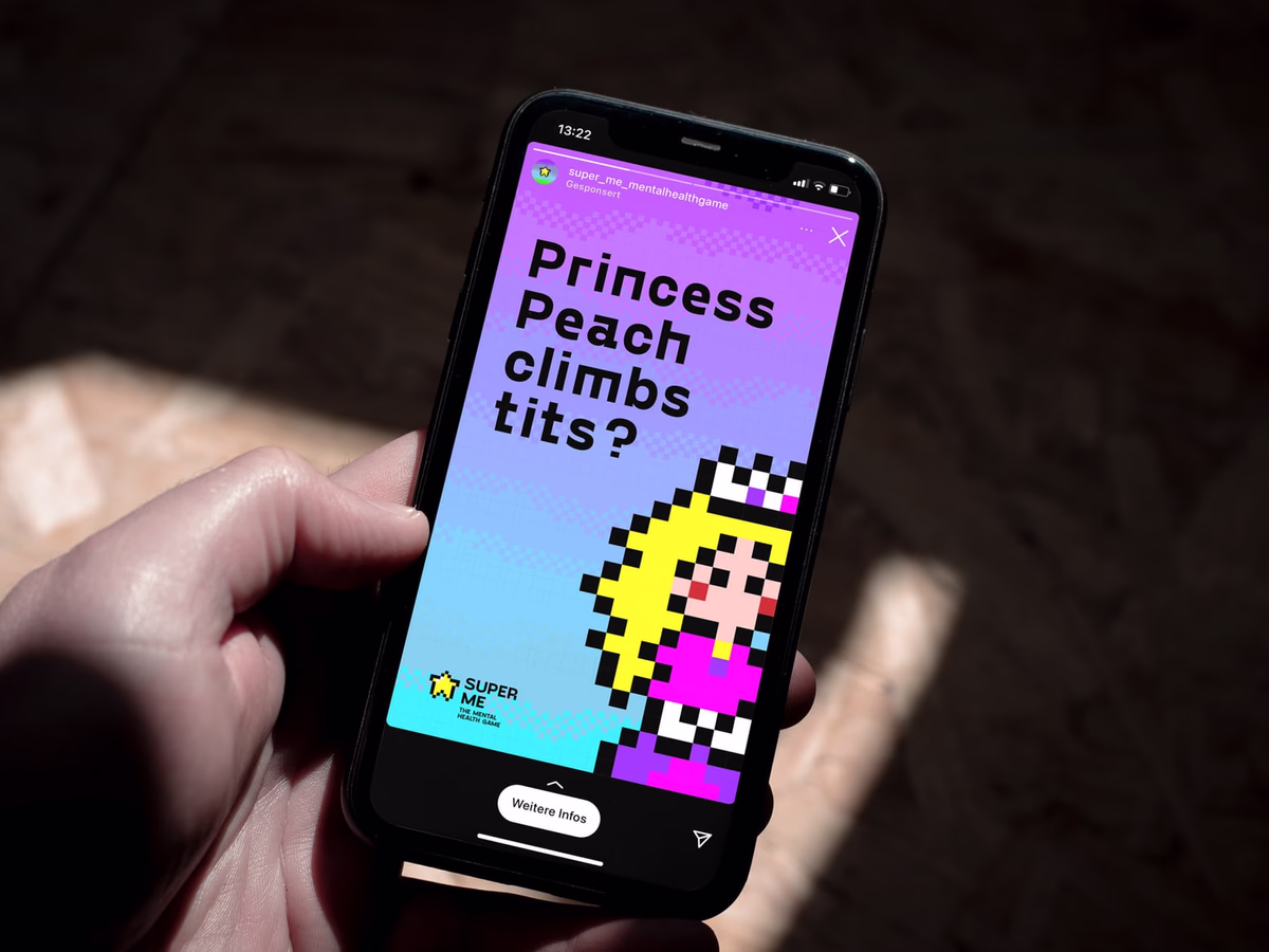 A hand holds a smartphone showing a magenta SUPER ME ad against blurred lights.