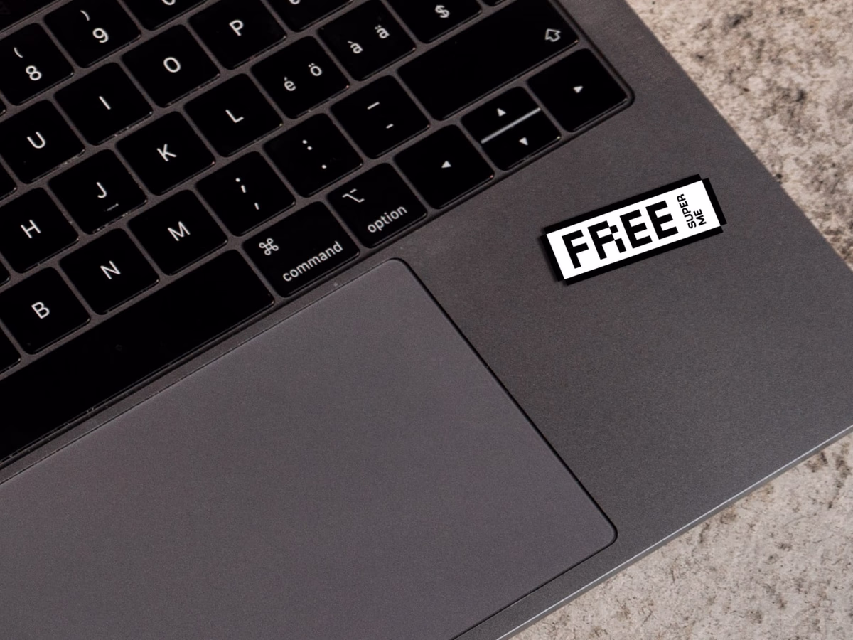 A bright-pink "FREE!" sticker stuck on the keyboard of a black laptop.