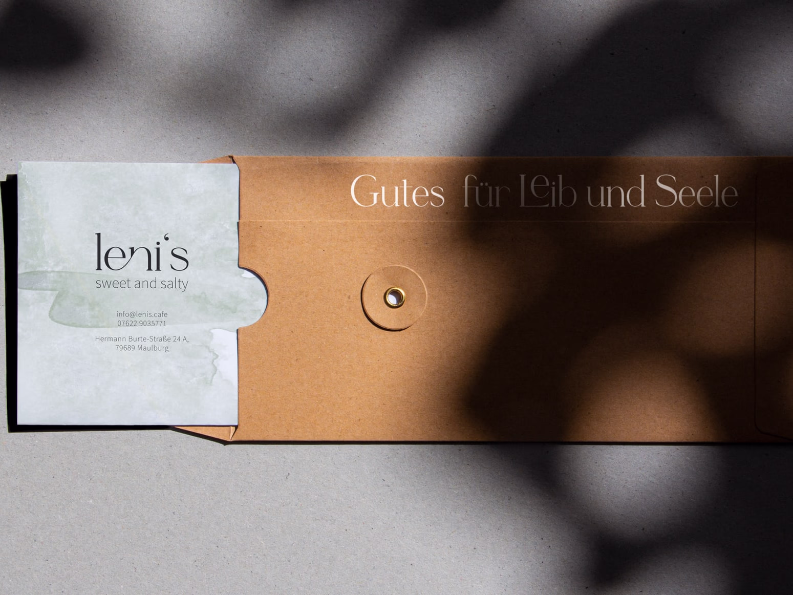 A watercolour card tucked into a leather sleeve next to the embossed line "Gutes für Leib und Seele".