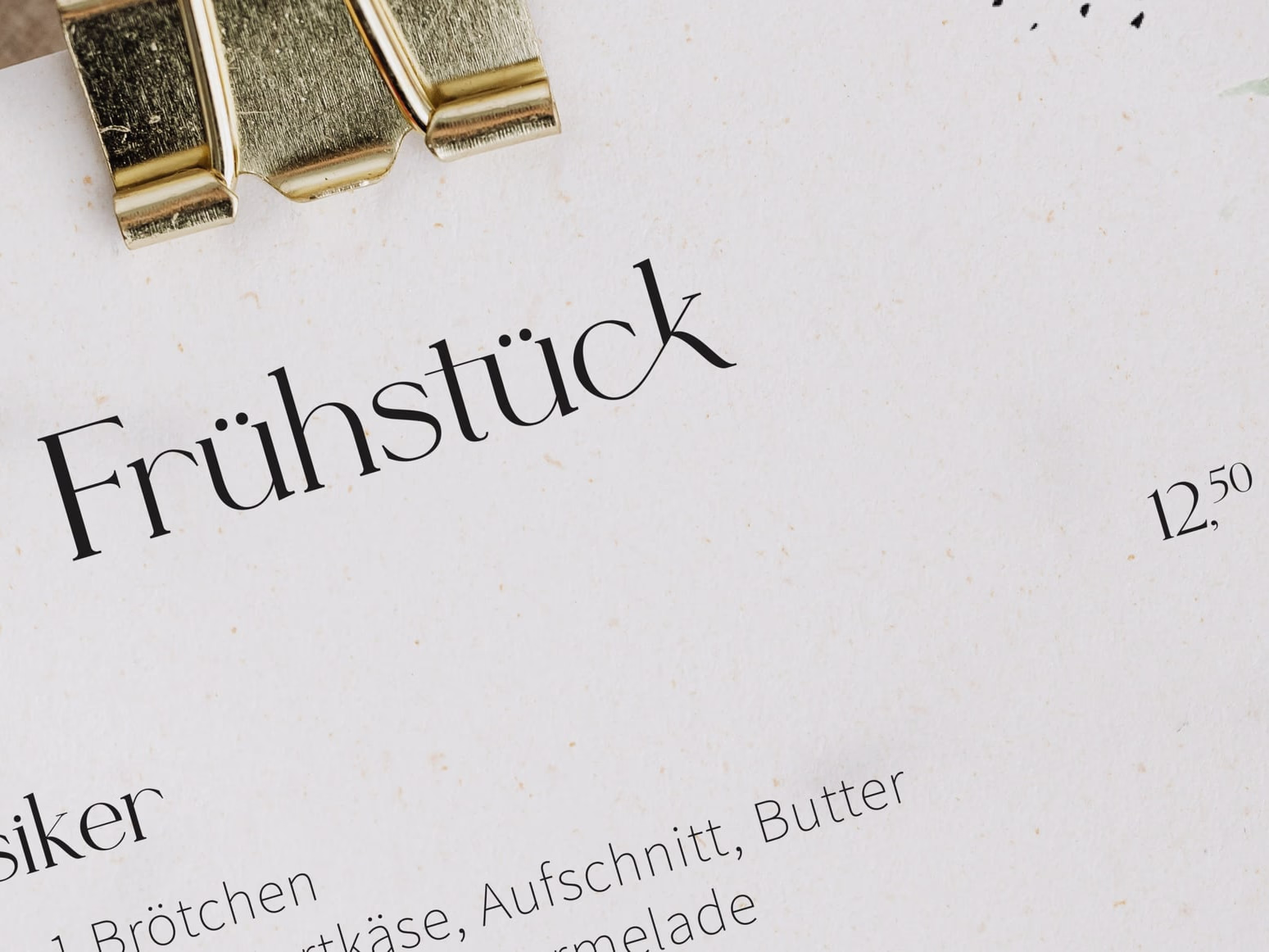 Open menu page headed "Frühstück", flanked on the left by gold-coloured stamp holders.